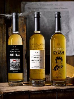 Drinks photograph of three limited edition Penderyn Welsh whiskies, three of their Icons of Wales series presented on a vintage apple crate with more vintage apple boxes in the background
