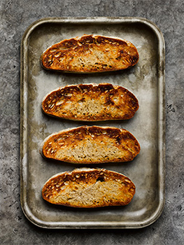 Aerial food photograph of sourdough toast, four slices of golden sourdough toast shot on a vintage baking tray, shot on a grey stone background