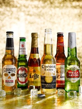 Drinks photograph of various bottled beers served on a glass sheet with a glittering gold background
