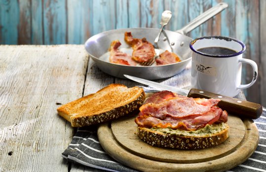Food photograph of a bacon sandwich with Welsh laverbread butter, shot in a nautical themed set with blue background and enamel tableware